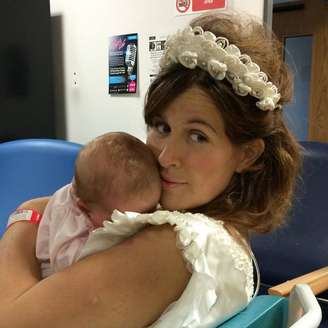 Vestida de noiva, Michelle O'Connor carrega a filha do casal