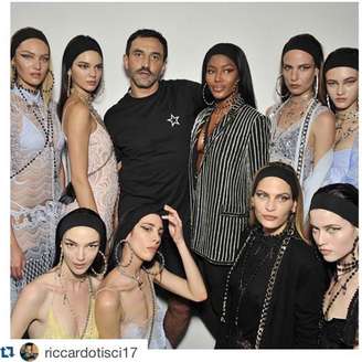 Riccardo Tisci com sua "gangue". A brasileira aparece agachada com faixa preta nos cabelos à direita da foto.