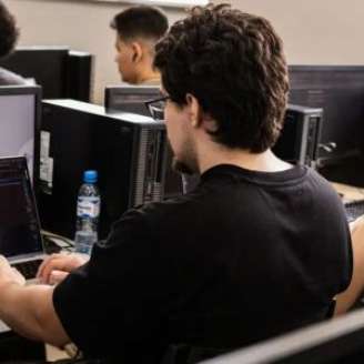Jovens realizando cursos em computadores.