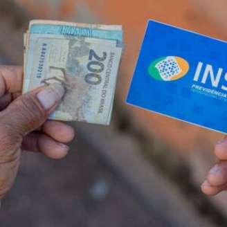 Pessoa idosa segurando cartão e benefício do INSS.