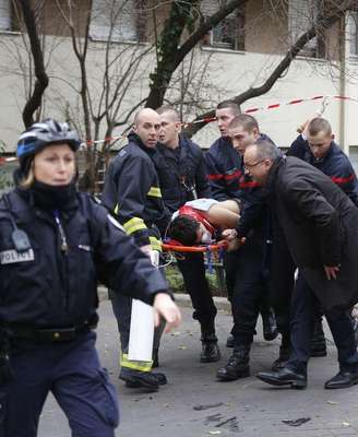 <p>Bombeiros levam vítima em maca após ataque a jornal satírico em Paris, em 7 de janeiro</p>