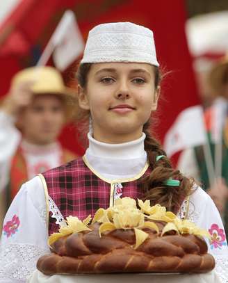Jovem com trajes típicos oferta o "pão e sal" tradicional de cerimônia russa