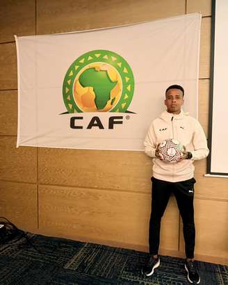 Omar Artan, árbitro da Somália, posa ao lado de bandeira da CAF 