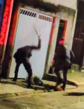 Homem é atingido por policiais militares com golpes de cassetete e chutes.