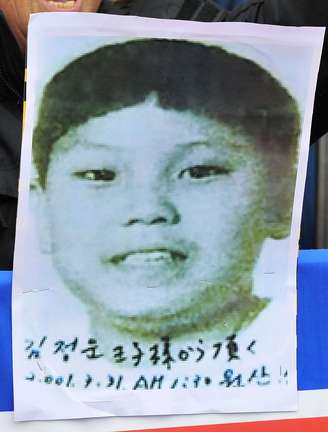 <p>Sul-coreanos exibem imagem de Kim Jong-un com cerca de 11 anos em protesto em Seul, em 2009. Esta é a única imagem da infância dele em circulação </p>