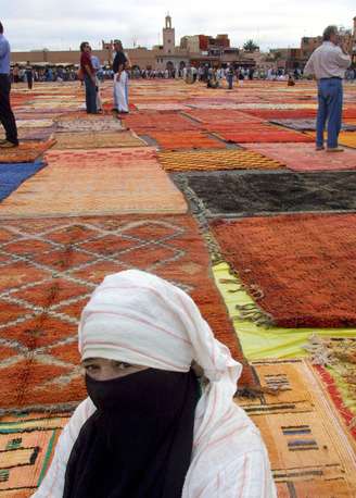 <p>Vendedora exibe tapetes marroquinos, um dos principais itens do comércio para turistas</p>