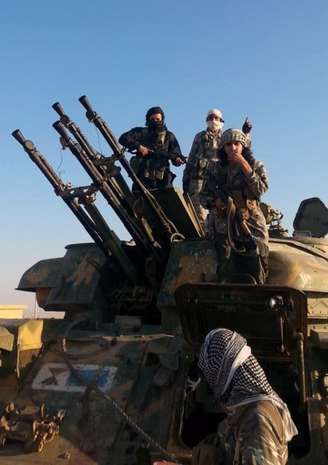 <p>Membros do grupo Estado Islâmico posam para foto no topo de um veículo militar com armas antiaéreas em Raqqa, na Síria</p><p> </p>