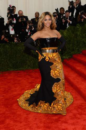 <p>A roupa de Beyoncé, da grife Givenchy, chamou a atenção tanto pela estampa “acesa” em volta de toda a saia, que parece que ela está no meio de uma fogueira, quanto pelos complementos, como bota, top e luvas. Em meio a rumores de gravidez, que a cantora nega, o look ainda ampliou a silhueta da moça</p>